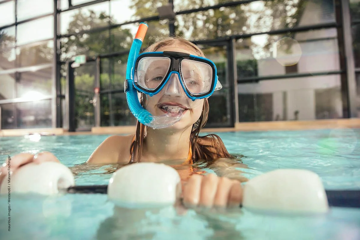 MÃ¤dchen mit Schwimmbrille und Schnorchel in einem Hallenbad. Damit keine Ohrenschmerzen folgen, heiÃŸt es, die Ohren grÃ¼ndlich abzutrocknen.