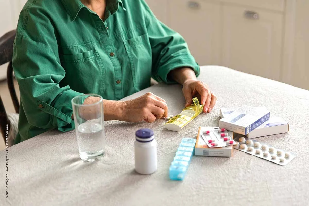 Ältere Frua sucht die richtigen Tabletten aus einem Stapel Schachteln heraus. Im Alter sind nicht alle Medikamente gut geeignet. Bei der Auswahl hilft die Priscus-Liste.