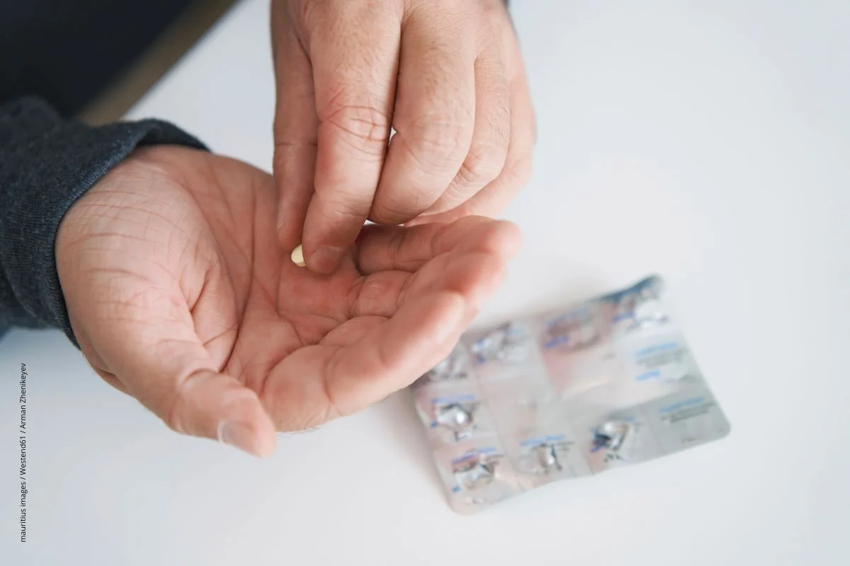 Ein Mann hält einen Blisten mit Schmelztabletten in der Hand.