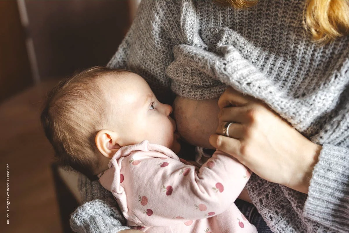 Kind wird an der Mutterbrust gestillt.