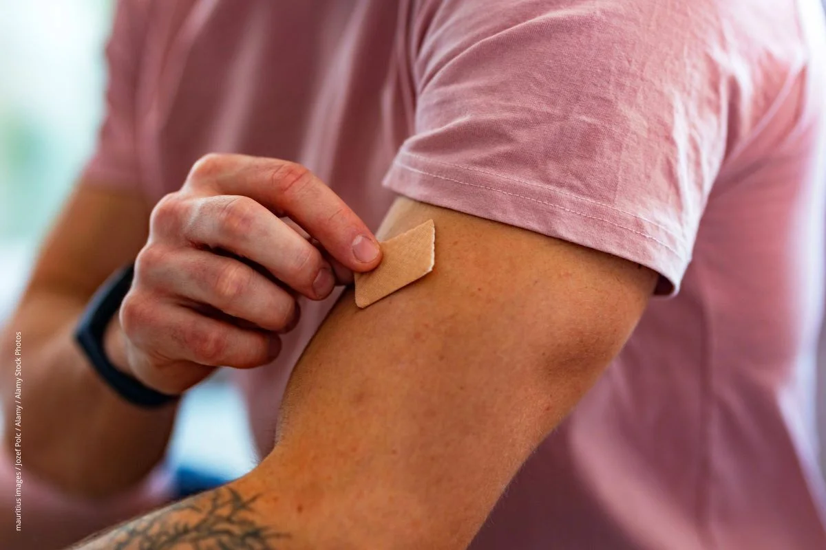 Mann hat ein Nikotinpflaster auf den Oberarm geklebt.