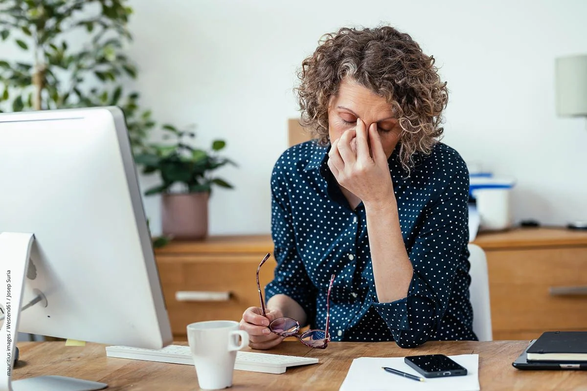 Frau mit Konzentrationsproblemen hinter ihrem Computer. Dem kann auch ein Vitaminmangel zugrunde liegen.