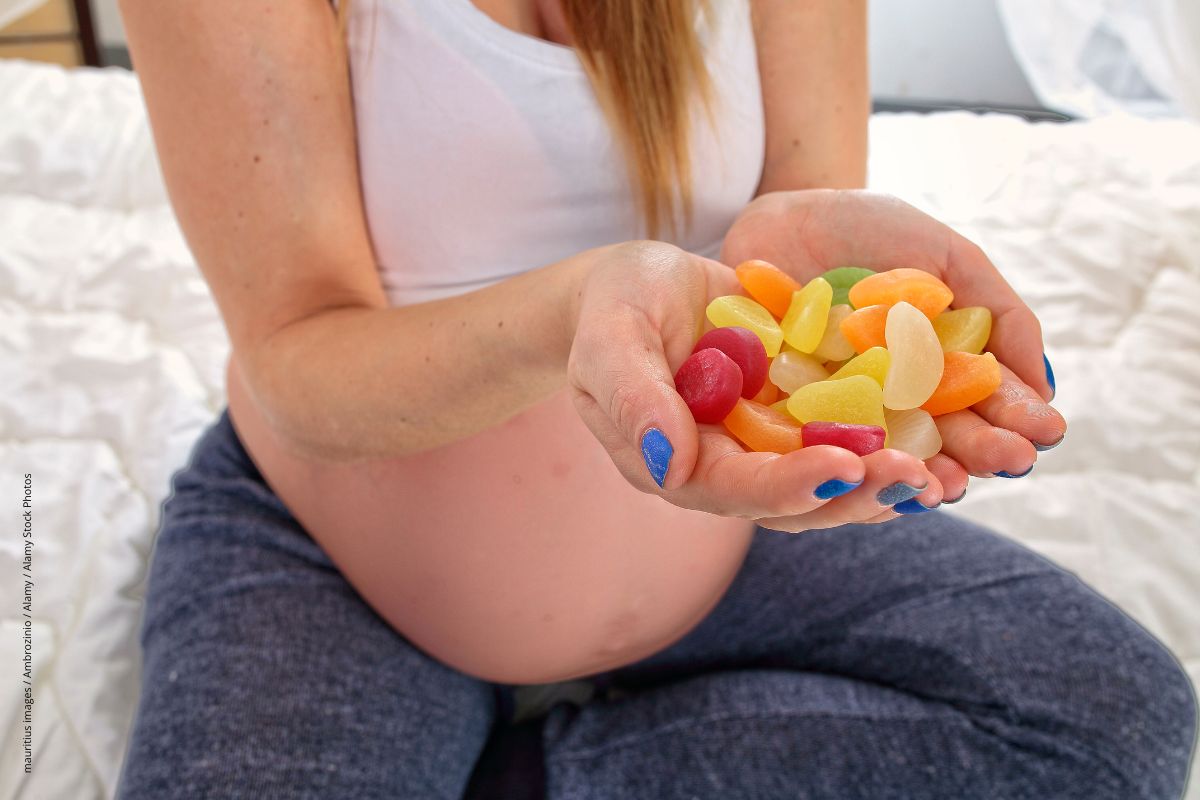 Schwangere hat die Hände voller süßer Fruchtgummis.