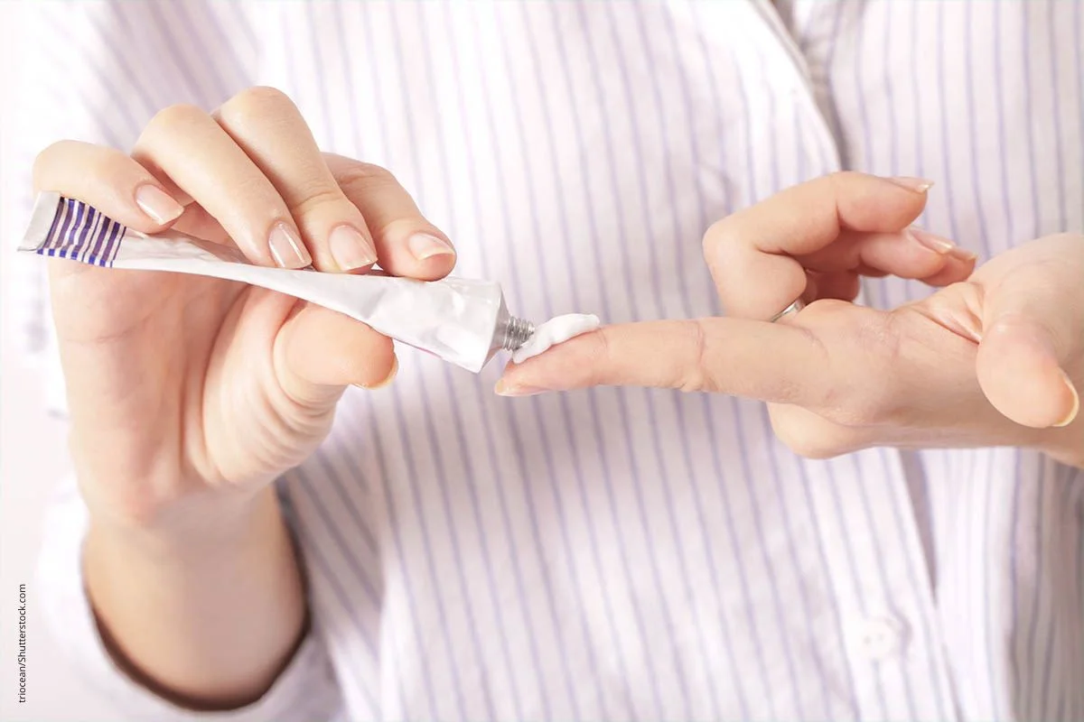 Person gibt Kortisonsalbe aus einer Tube auf den Finger.