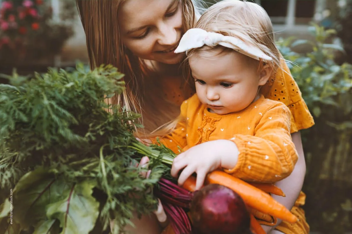 Mutter und Kind mit frisch geernteter Karotte. Bei aller Begeisterung fÃ¼r Veganismus dÃ¼rfen gerade bei Kindern die Vitamine nicht vergessen werden.
